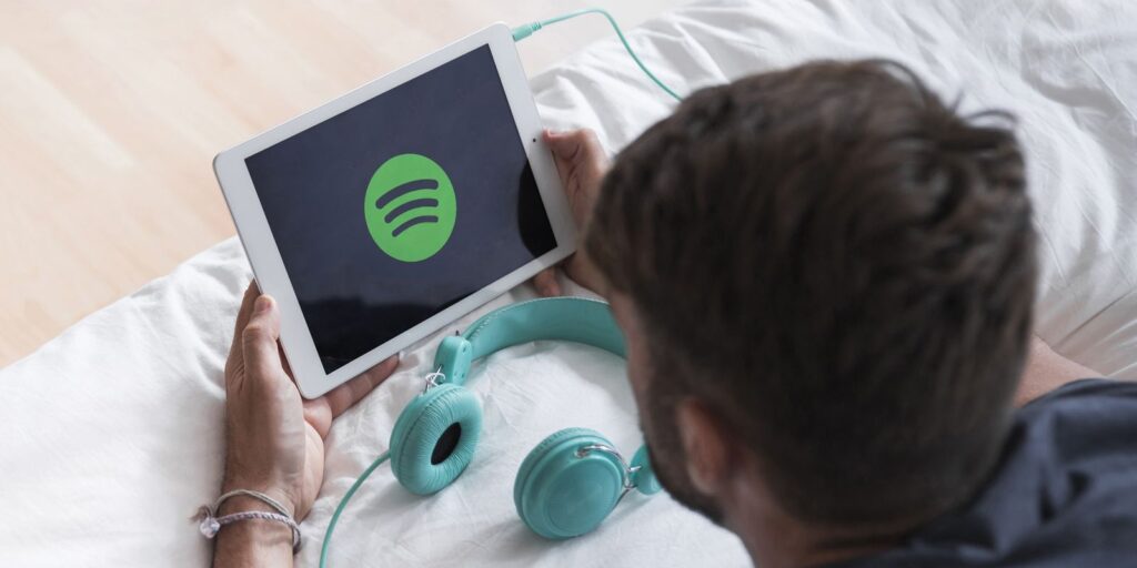 young-man-holding-modern-device-with-spotify-app.jpg